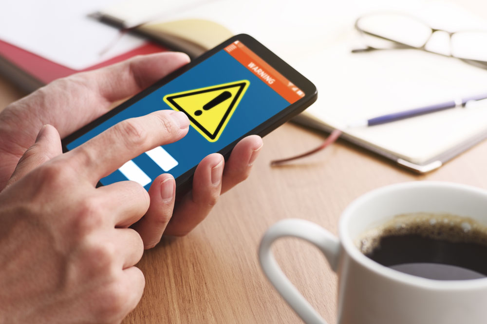 Mann hält Smartphone mit Warn-Meldung in der Hand Smartphone Warnung